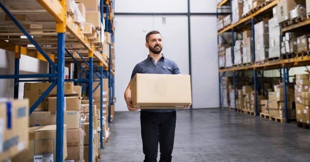 Homem segurando caixa em depósito de e-commerce